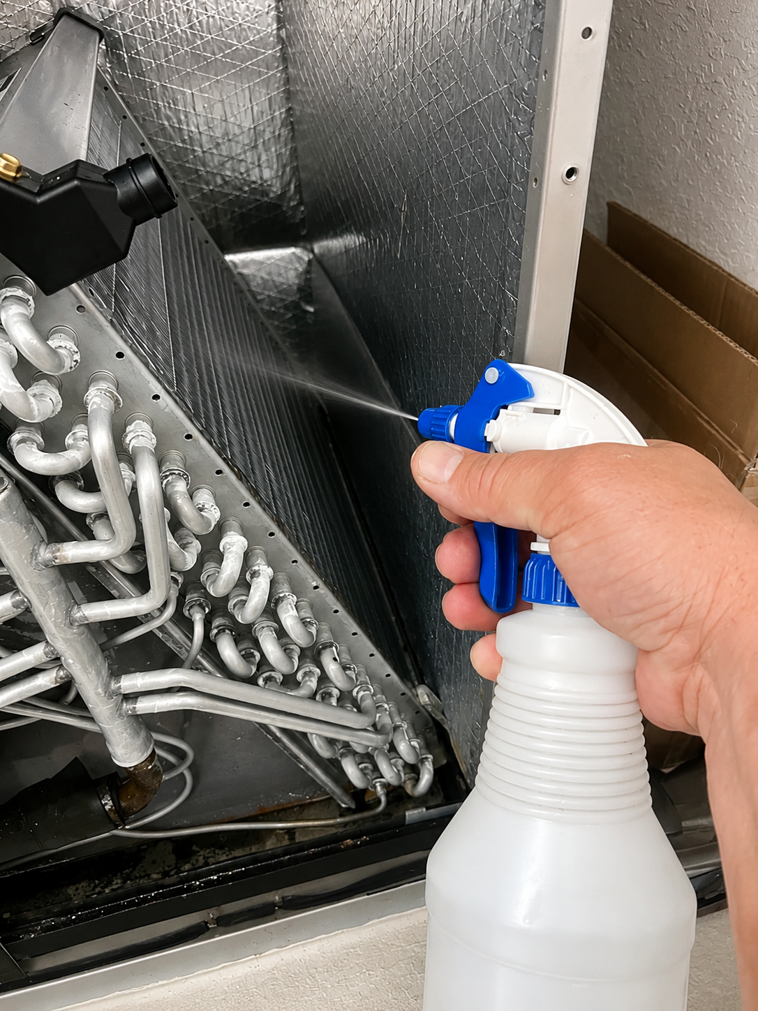 A hand spraying a foam coil cleaner inside an AC system